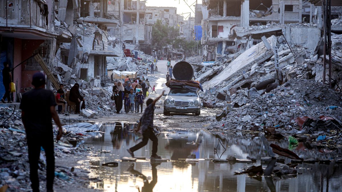 Palestinians walk past sewage flowing into the streets of the southern town of Khan Younis, Gaza Strip